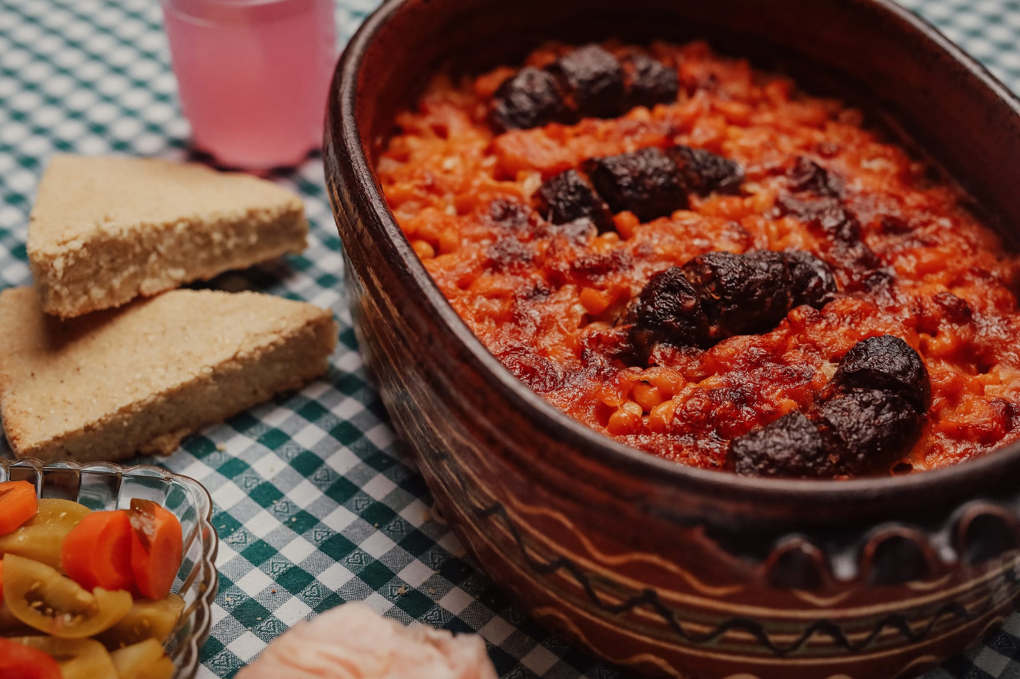 Baked beans with sausage in a clay dish, the kind of slow-cooked Balkan dish served at a family table